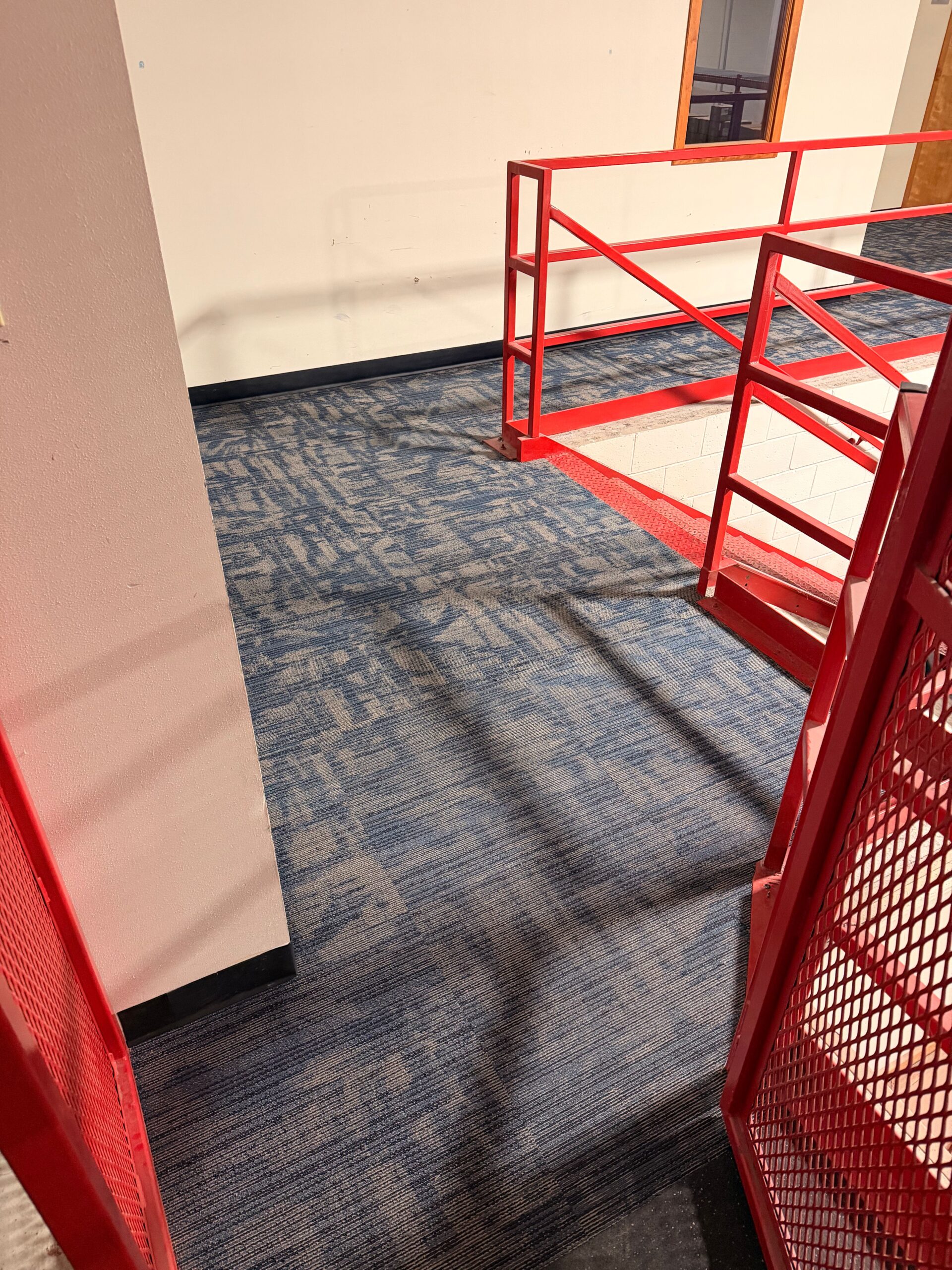 Finished blue patterned carpet tile around the stair opening